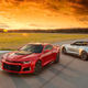 Two Chevrolet Camaro sports cars parked at sunset.